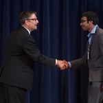 Doctor Smart shaking hands with an award recipeint in a grey suit